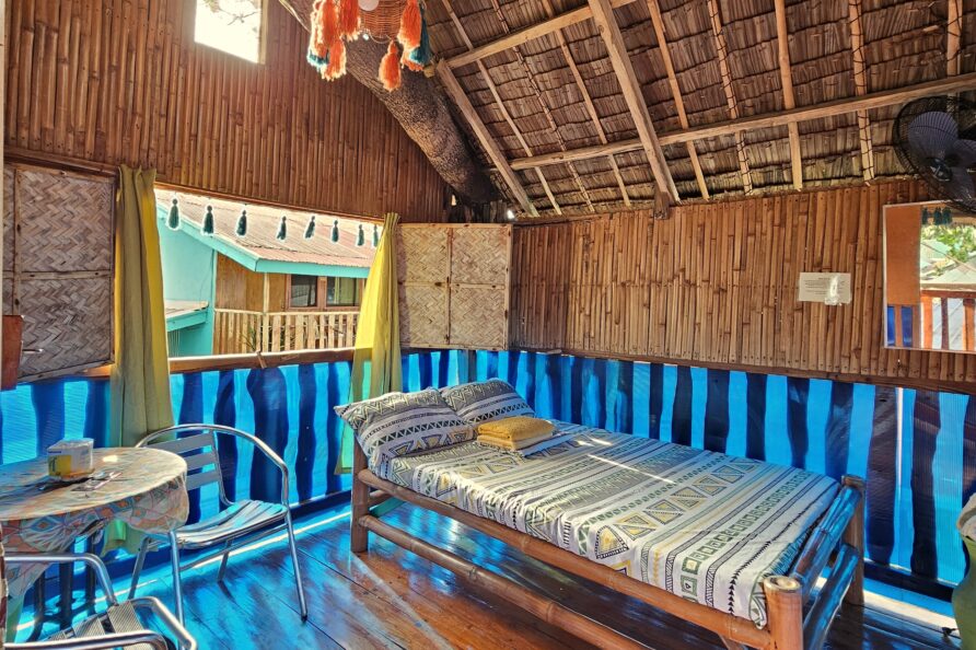 Cozy interior layout of the Affordable Treehouse Room San Carlos, featuring a table for two, natural wood, bamboo, and nipa materials.