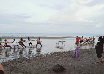 Team activity tug of war on beach for large group family reunion games