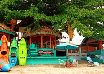 Kayaks on beach with seaside cottages and large shady tree for family reunion venue bacolod