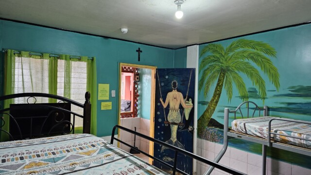 Mermaid room sleeping quarters with palm tree mural and colorful beds for family reunion venue accommodation