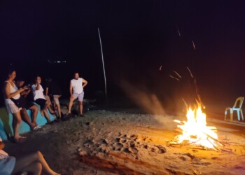 Group watching large beach bonfire and campfire during family reunion venue social activities