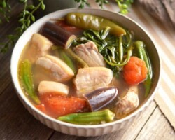 A Filipino Classic, Elevated. Our Signature Pork Sinigang is a house favorite, featuring a bold, rich tamarind broth. Experience authentic, high-quality Filipino specialties served right next to the sea. Signature Pork Sinigang soup with vegetables, a house favorite Filipino dish near San Carlos City