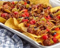 The Famous Chili Cheese Nachos. Layered with real melted cheddar cheese, premium chili, and Genuine Tostito's chips—a hard-to-find treat and the perfect sharing platter for your seaside dining experience. Chili Cheese Nachos with Tostito's chips and melted cheese at the pub near San Carlos City